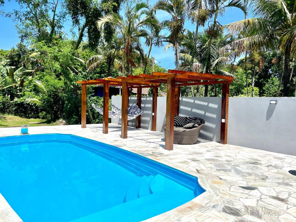 a swimming pool with a wooden pergola and a swimming pool at Sunset Maresias- Casas e Chalés C1 in Maresias