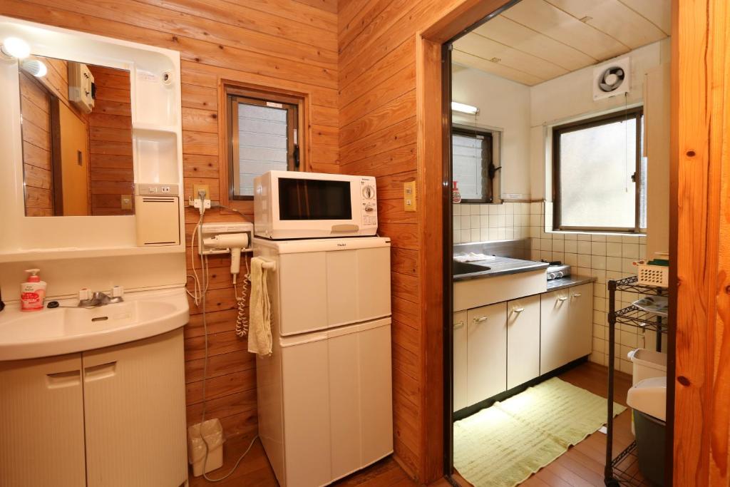 a kitchen with a sink and a microwave at Kurasako Onsen Sakura in Minamioguni