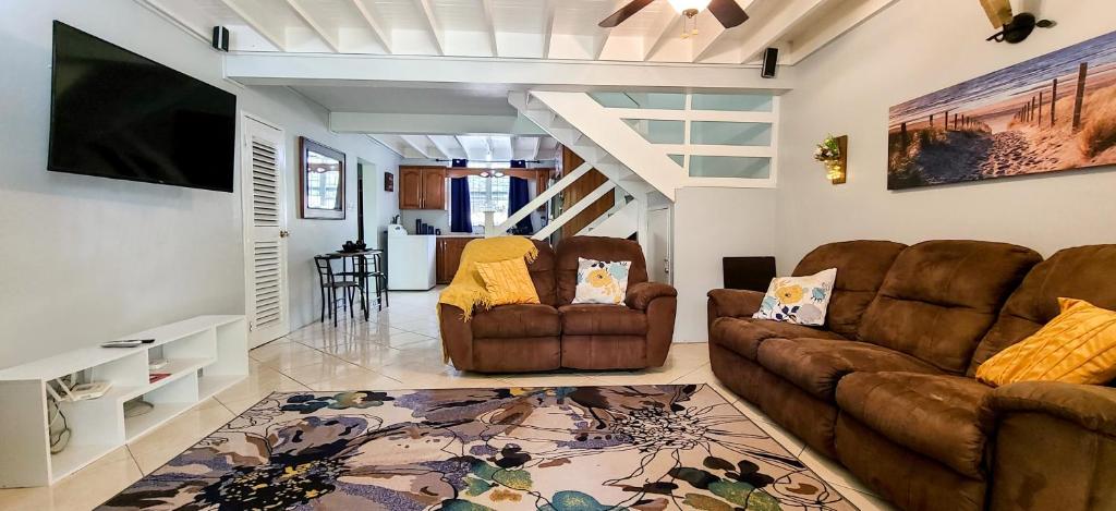 a living room with two couches and a flat screen tv at Cheerful 2 - Bedroom Townhouse with free parking in New Kingston in Kingston
