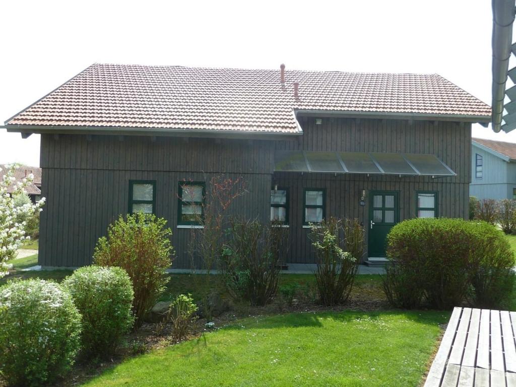 una casa con techo marrón y algunos arbustos en Ferienhaus Nr 16B2, Feriendorf Hagbügerl, Bayr Wald en Waldmünchen