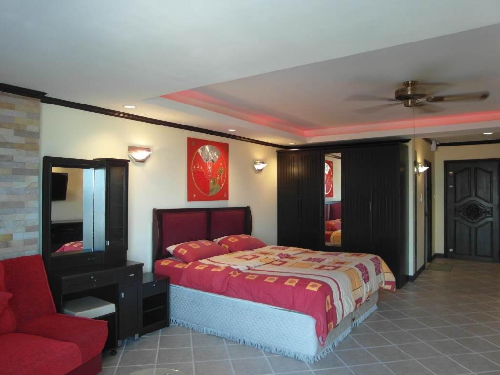 a bedroom with a bed and a red chair at View talay Vt2a F5 R207 in Pattaya South
