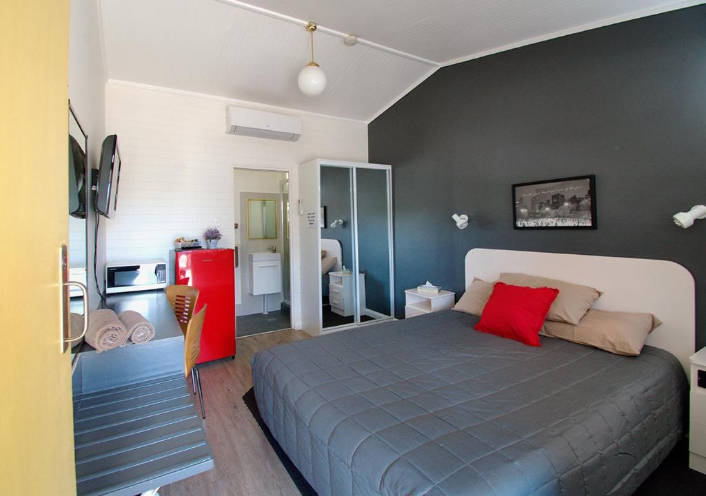 a bedroom with a bed and a red refrigerator at Memphis Motor Inn in Parkes