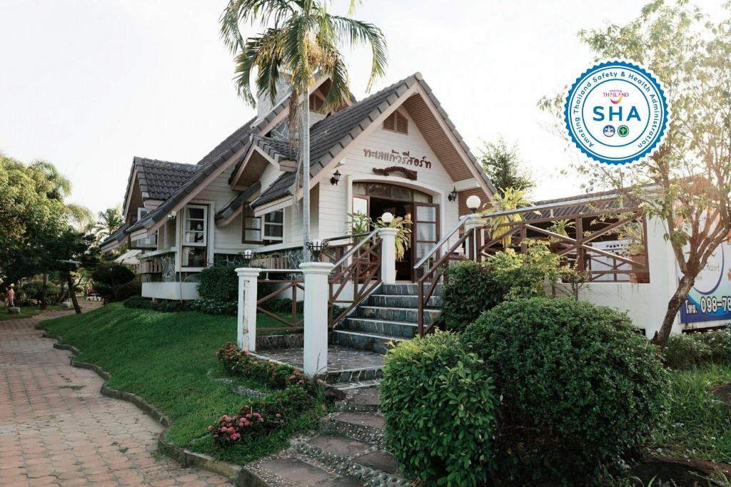 a house with a palm tree in front of it at TaLeKaew Resort SHA in Phitsanulok