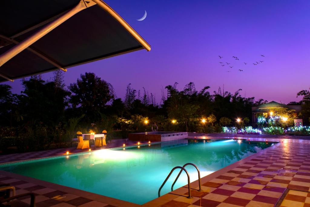 una piscina por la noche con la luna en el cielo en Olive Resort - Sillari Pench en Silāri
