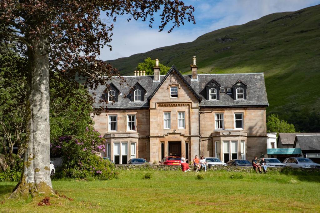 une vieille maison avec des voitures garées devant elle dans l'établissement The Caledonian Claymore Hotel, à Arrochar