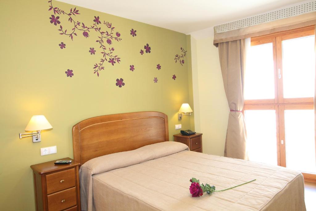 a bedroom with a bed with purple flowers on the wall at Hostal Campo Real Bed&Breakfast in Campo Real