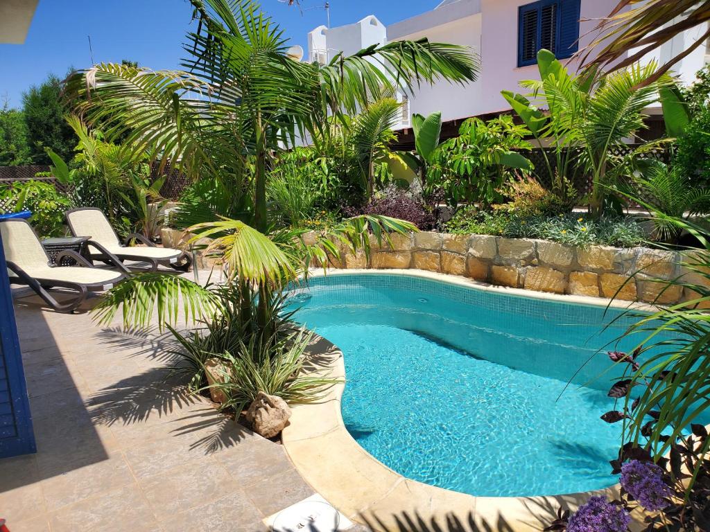 uma piscina num quintal com cadeiras e árvores em Charming 3-Bed Villa in Protaras with heated pool em Protaras