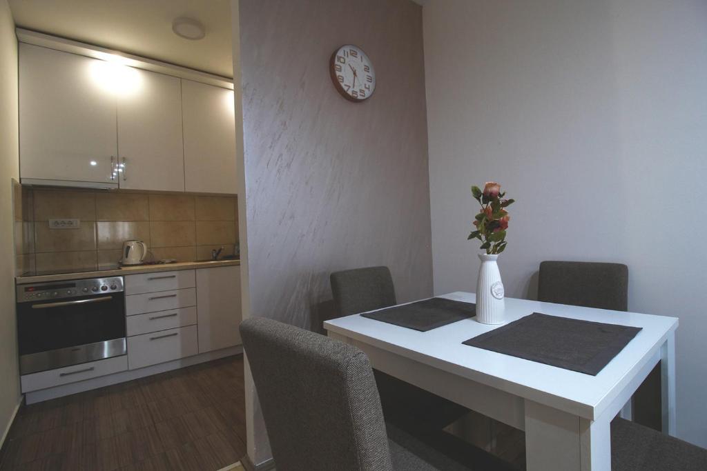 a kitchen with a table with chairs and a clock on the wall at TOP Apartman in Šabac