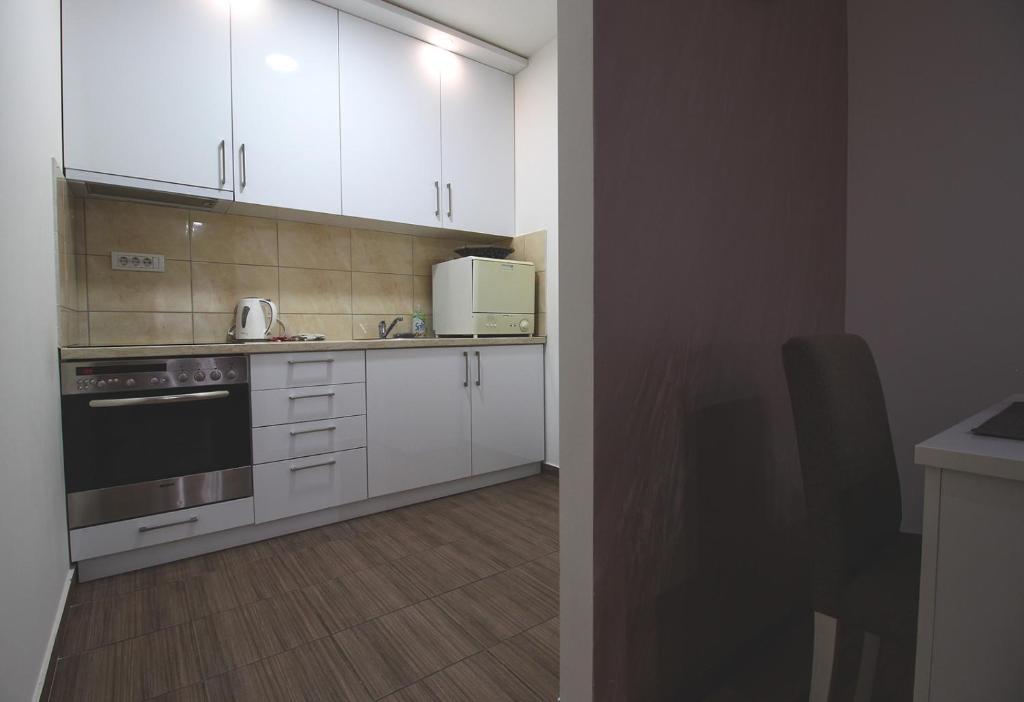a kitchen with white cabinets and a stove top oven at TOP Apartman in Šabac