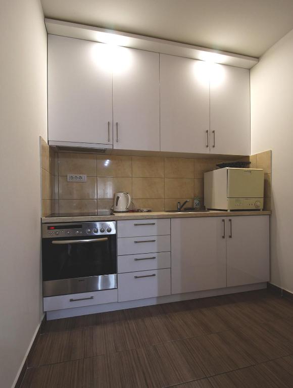 a kitchen with white cabinets and a stove and a microwave at TOP Apartman in Šabac