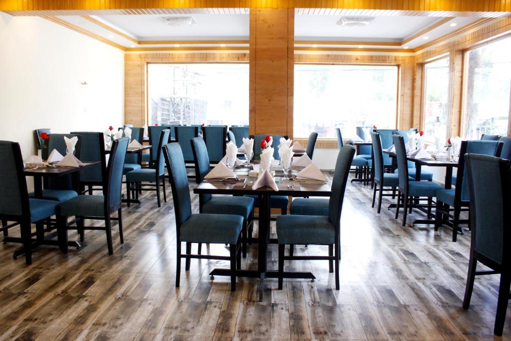 a dining room with tables and chairs and windows at Legend Hotel Skardu in Skardu