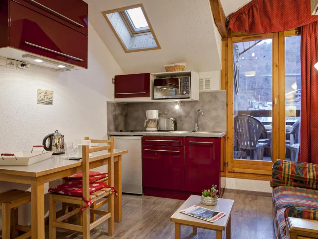 een keuken met rode kasten en een tafel in een kamer bij Appartement Brides-les-Bains, 1 pièce, 4 personnes - FR-1-512-204 in Brides-les-Bains