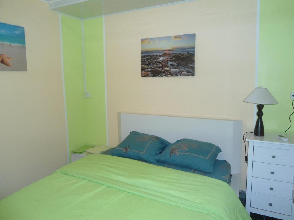 a bedroom with a green bed and a white dresser at Les Meublés Les Dauphins in Étang-Salé les Bains