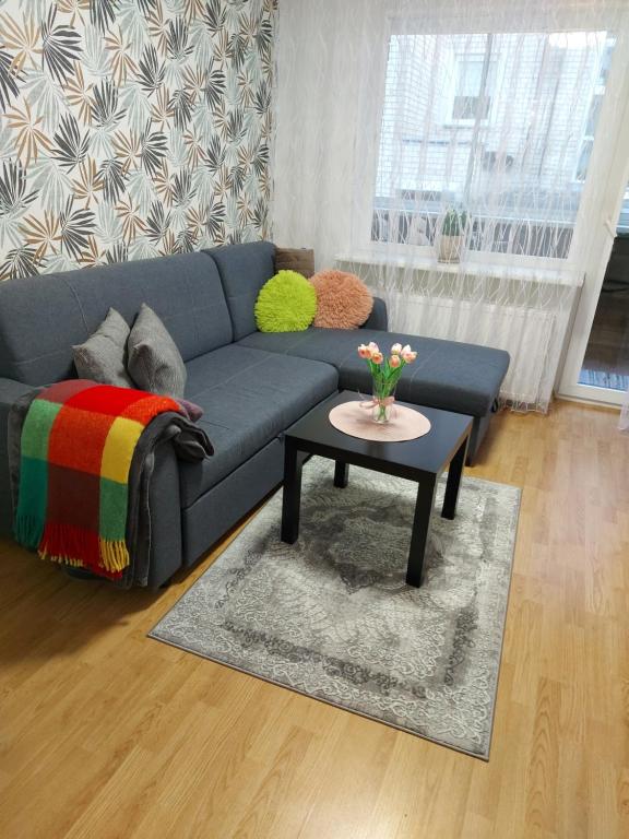 a living room with a blue couch and a table at Apartamentai „Kaip namuose“ in Druskininkai