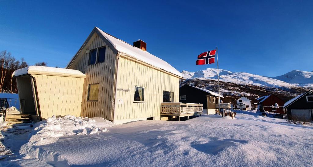 un edificio en la nieve con bandera canadiense en Lyngen Arctic View, en Olderdalen