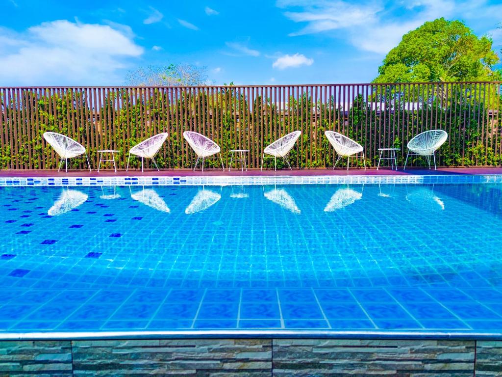 a swimming pool with chairs and a fence and a swimming pool at Lueangchan Orchid Hotel in Chanthaburi