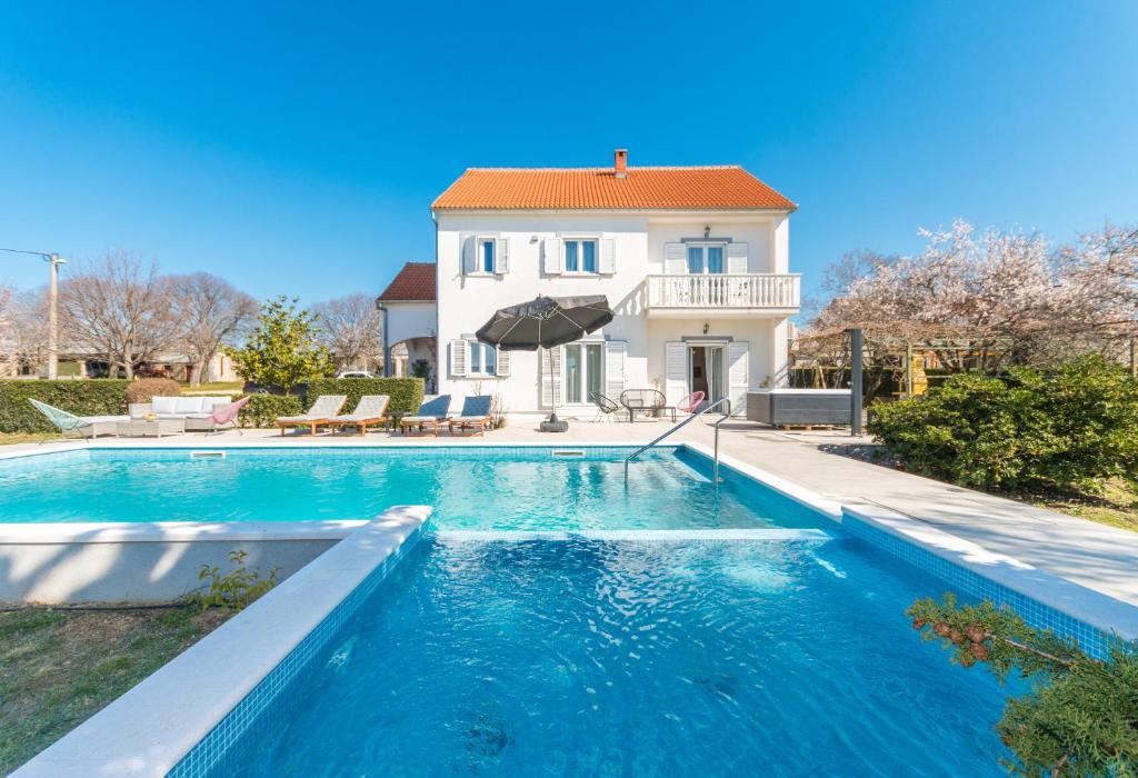 une villa avec une piscine en face d'une maison dans l'établissement Spacious villa Vito with large pool, à Tinj