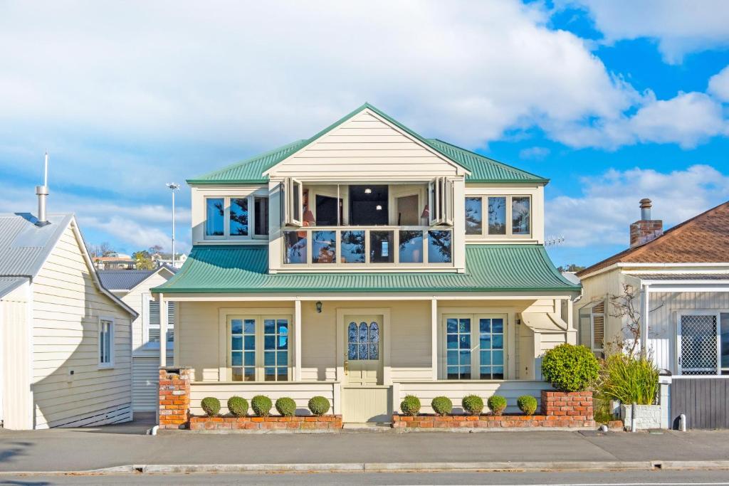 Biały dom z zielonym dachem w obiekcie Beachfront Villa w mieście Napier