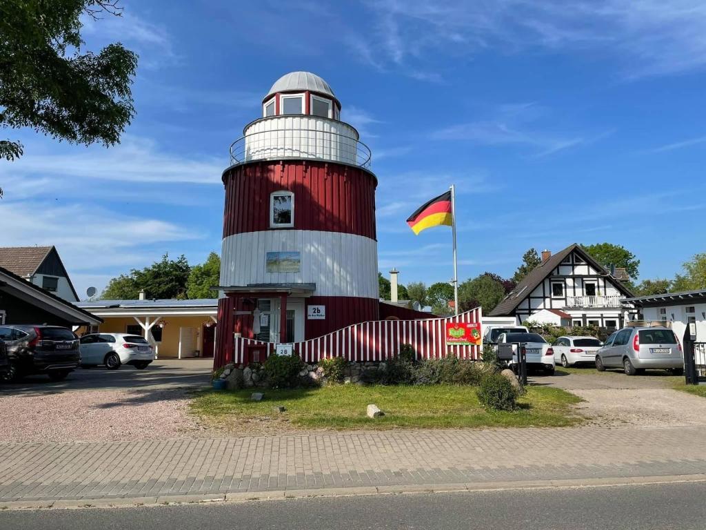 a red and white lighthouse with a flag in a parking lot at Ferienhaus Leuchtturm in Börgerende-Rethwisch