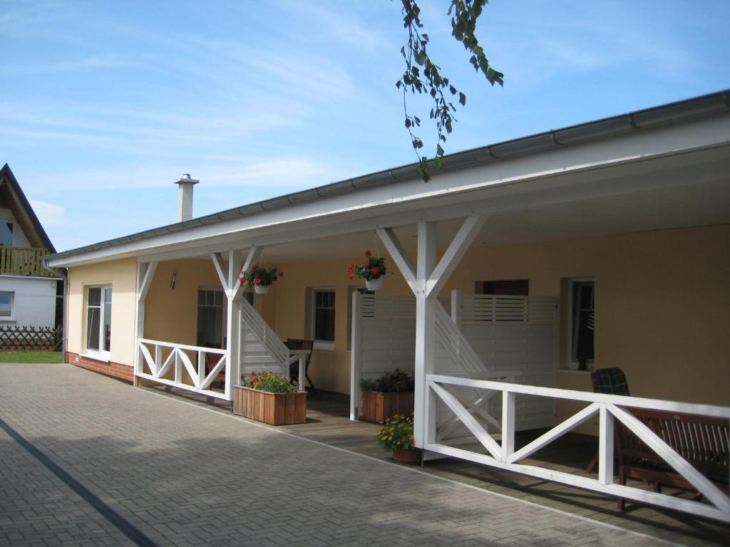 ein Haus mit einer Veranda mit einem weißen Dach in der Unterkunft Leuchtfeuer Fewo "Andersen" in Börgerende-Rethwisch