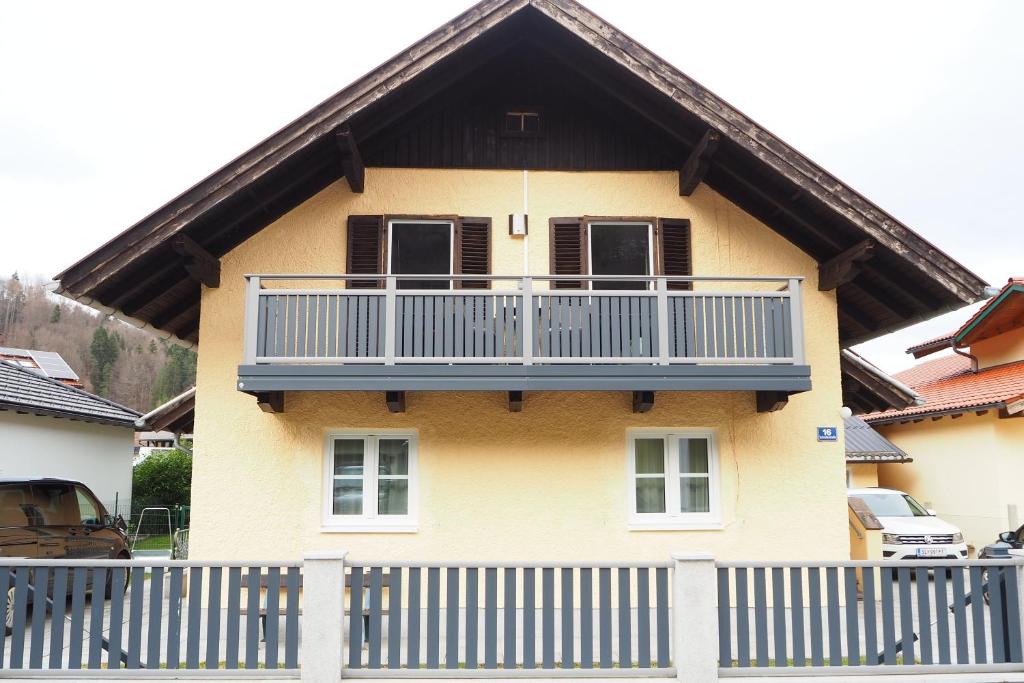 une maison jaune avec un balcon au-dessus dans l'établissement Ferienwohnung Fürstenbrunn, à Grödig