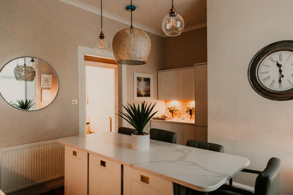 a kitchen with a table and a clock on the wall at Unique Beach 2 bedroom town house, Golf Paradise in Prestwick