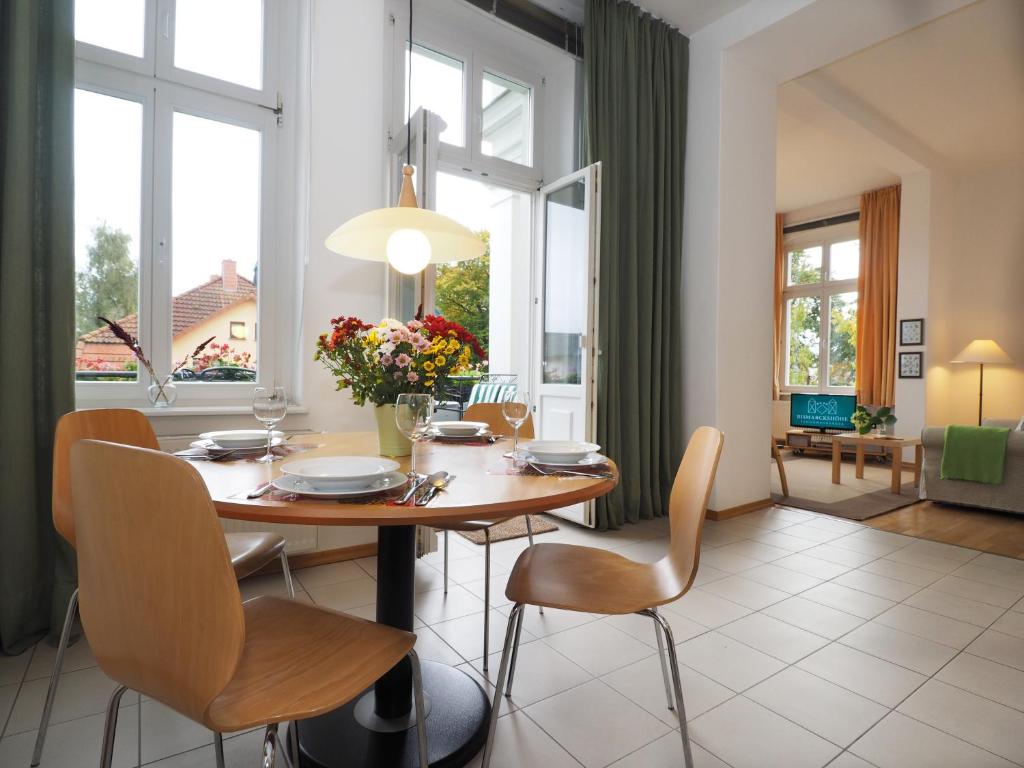 comedor con mesa, sillas y ventanas en Villa Bismarckshöhe Wohnung Gertrud, en Ahlbeck