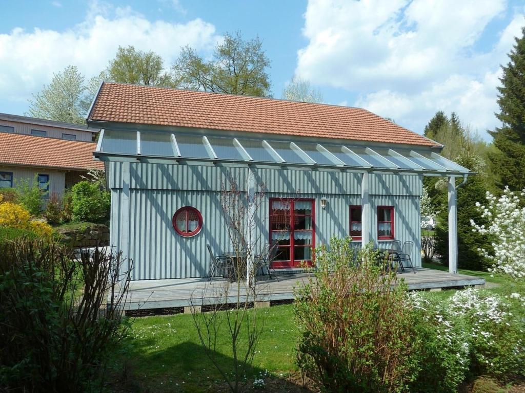 uma pequena casa cinzenta com uma janela vermelha e um telhado em Ferienhaus Nr 15C, Feriendorf Hagbügerl, Bayr Wald em Waldmünchen