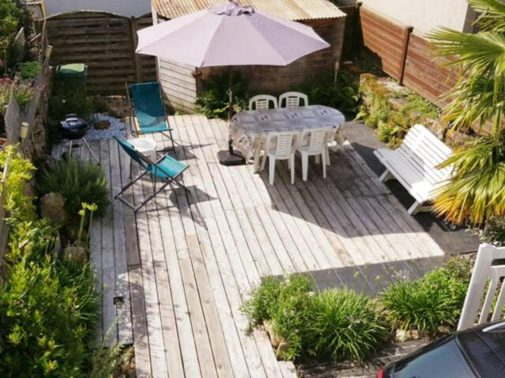 een patio met een tafel en stoelen en een parasol bij La Petite Maison de Kergroix // Mer et Maisons in Carnac