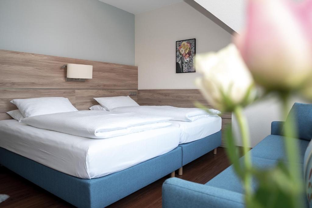 a bedroom with a bed and a blue couch at Hotel Kastanienhof in Erding