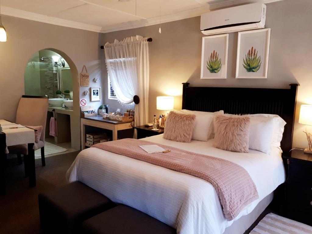 a bedroom with a large bed and a bathroom at The Village Inn in Polokwane