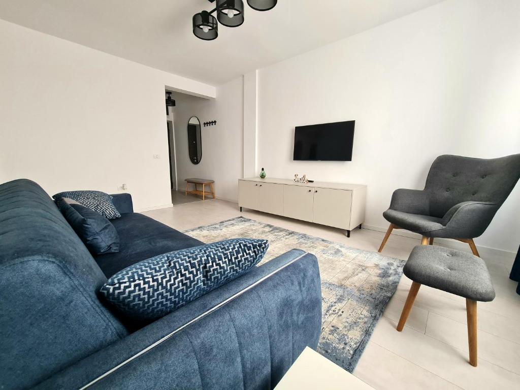 un soggiorno con divano blu e sedia di Dolphin Apartment near Neversea Beach a Constanţa