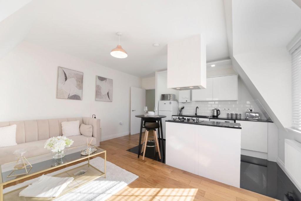 a white kitchen and living room with a couch at Spacious One Bed loft Apartment in Birchanger
