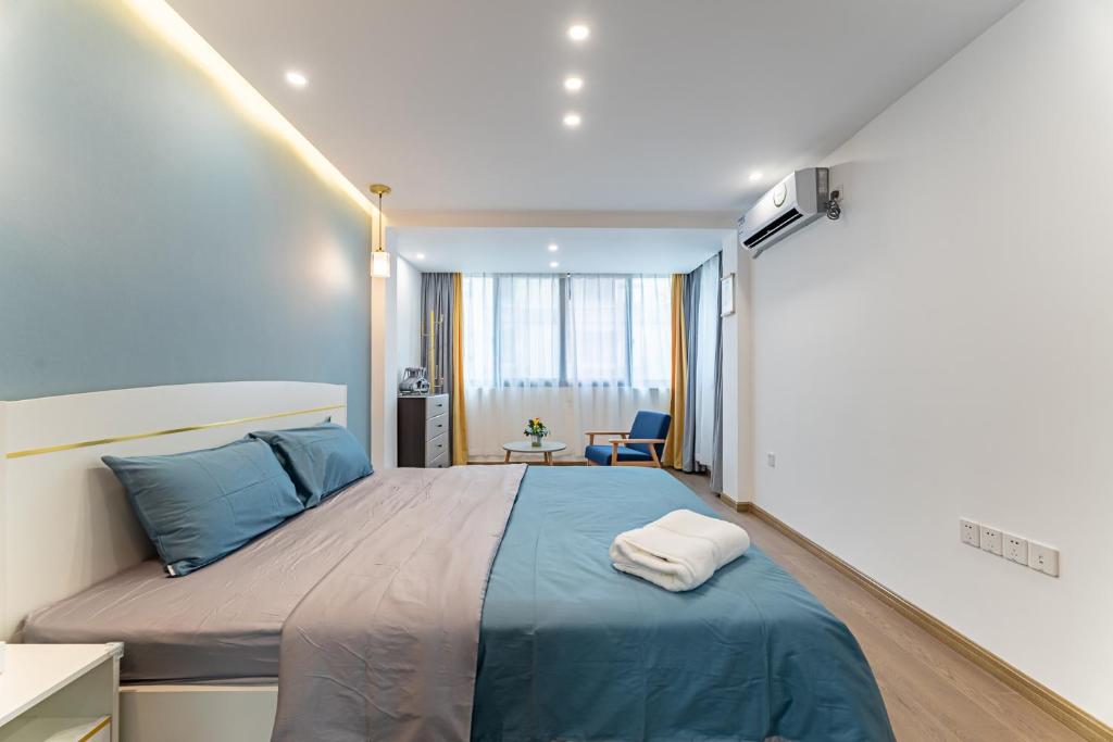 una camera da letto con un grande letto con lenzuola blu di Locals Apartment Place 99 a Hangzhou