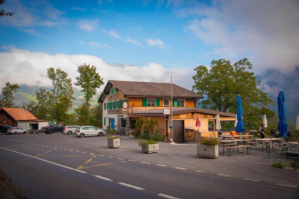 um edifício ao lado de uma estrada com mesas e guarda-chuvas em Hotel Cafe Seeblick em Filzbach