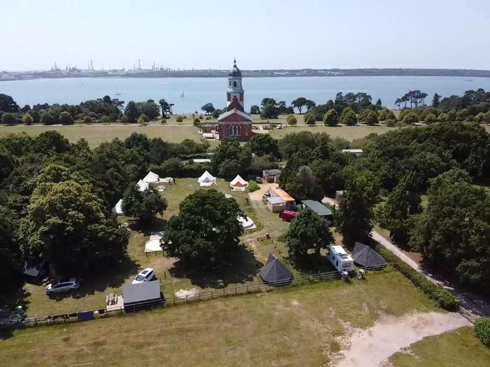 an aerial view of a farm with tents and a lighthouse at Bell Tent Glamping at Royal Victoria Country Park in Southampton