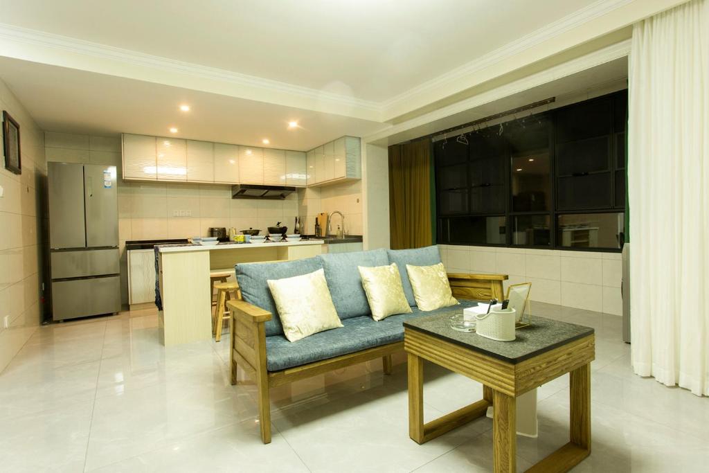 a living room with a blue couch and a kitchen at Locals Apartment House 19 in Zhenhai