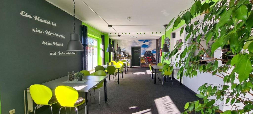 un ristorante con sedie gialle, tavoli e piante di Harz Hostel a Wernigerode
