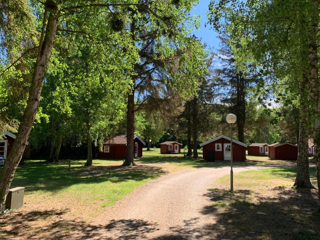un chemin de terre traversant une forêt avec des bâtiments rouges dans l'établissement Nordskoven Strand Camping, à Rønne