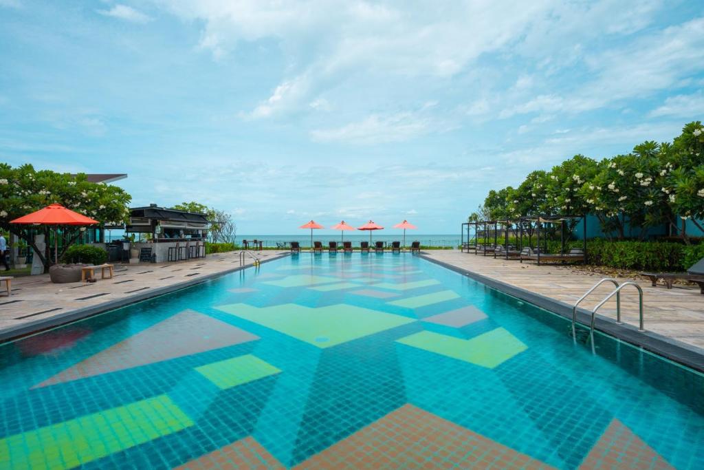 a swimming pool with a view of the ocean at Coral Tree Villa Huahin in Cha Am