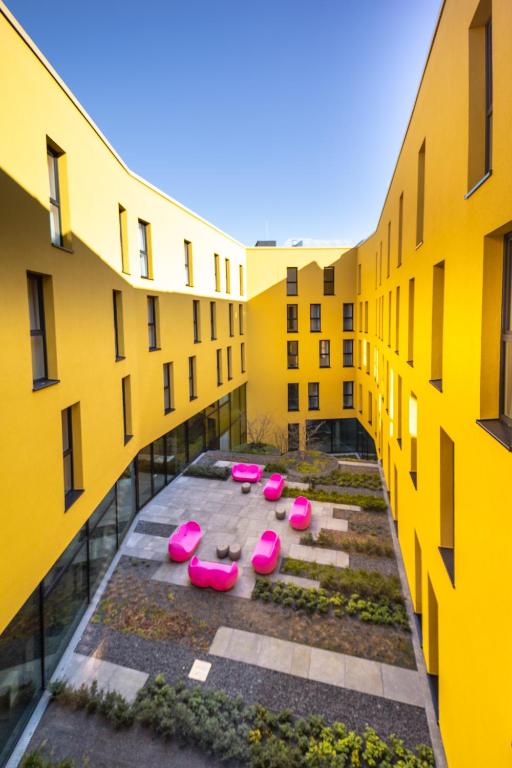 a row of pink chairs in a courtyard between two buildings at Prize by Radisson, Bonn City in Bonn