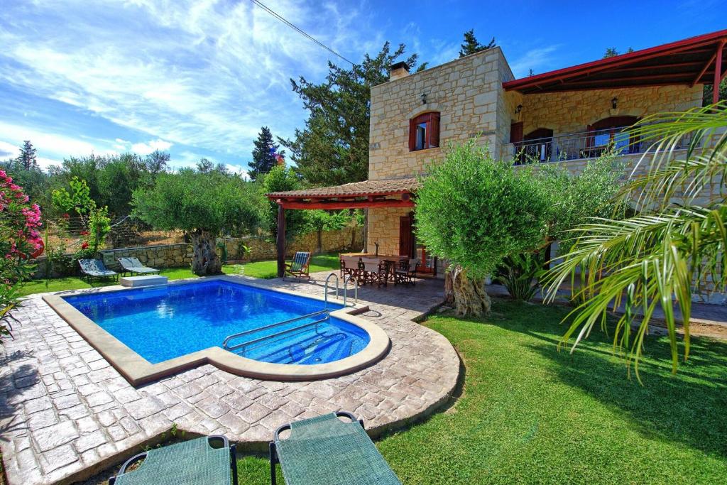 a backyard with a swimming pool and a house at Villa Nipos by PosarelliVillas in Vryses