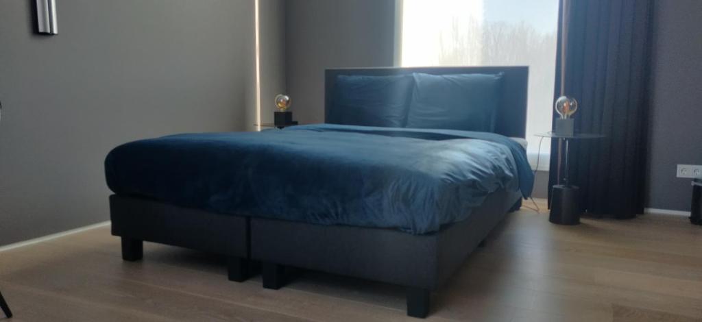 a bedroom with a blue bed with a blue comforter at Bed & Wellness Boxtel, luxe kamer met airco en eigen badkamer in Boxtel