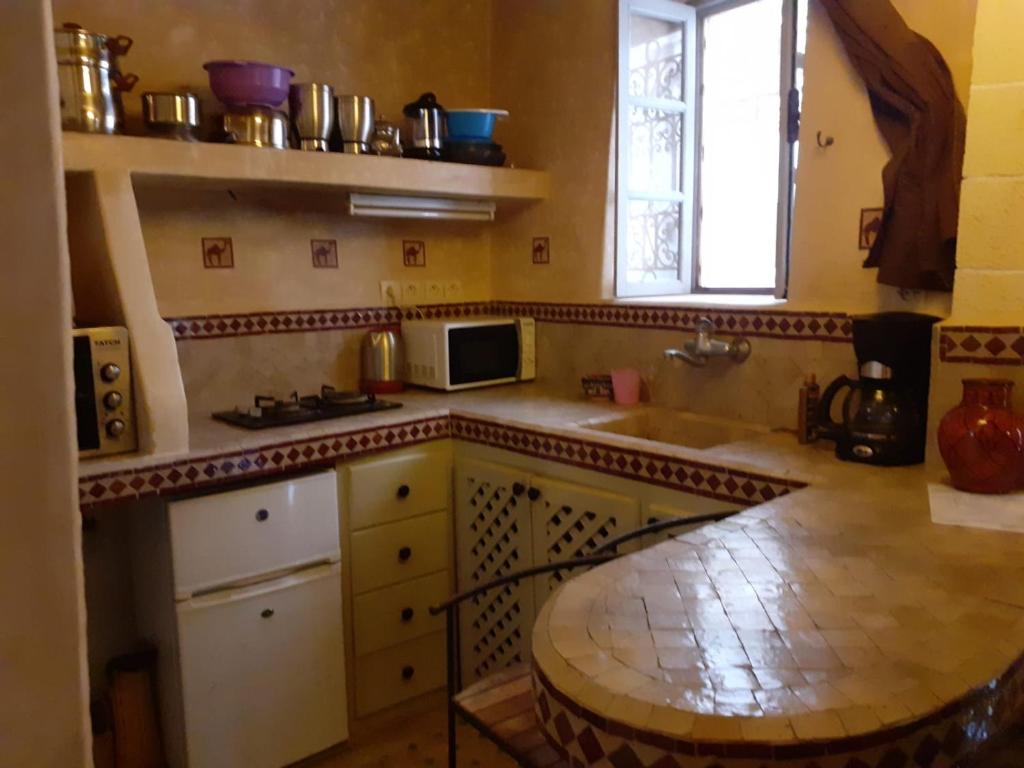une cuisine avec une table, un évier et une fenêtre dans l'établissement Dar Farah, riad au coeur de la médina, à Essaouira