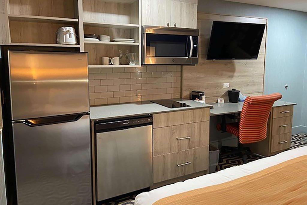 a kitchen with a stainless steel refrigerator and a desk at Ramada by Wyndham Medicine Hat in Medicine Hat