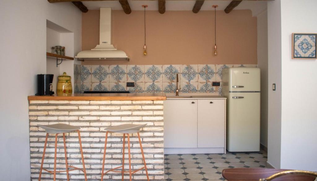 eine Küche mit einem weißen Kühlschrank und 2 Barhockern in der Unterkunft Casa rural Biota in Biota