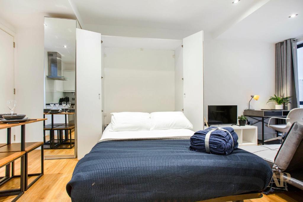 a bedroom with a bed with a blue blanket on it at Spacious Studio Apartment with private patio near Warren Street in London