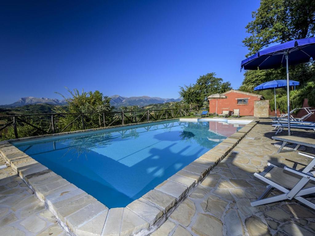 a swimming pool with two chairs and an umbrella at Belvilla by OYO La Priora in Monte San Martino