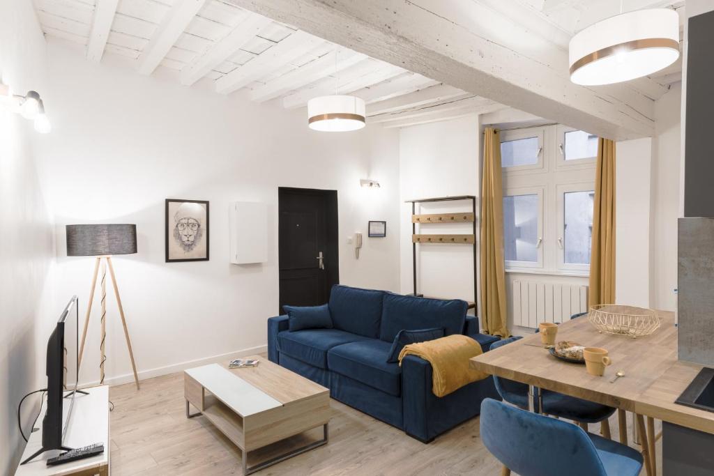 un salon avec un canapé bleu et une table dans l'établissement Le Nid du Lion - Joli T2 quartier St Georges au calme, à Lyon