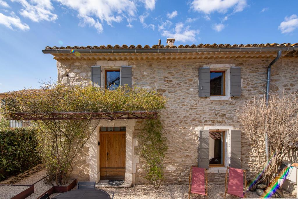 a stone house with a wooden door and windows at Le Mas des Sablières in Oppède